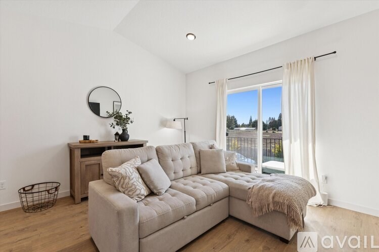 A living room with a grey sofa and a round mirror on the wall.