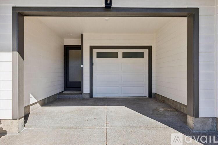 A garage door is closed and there is a black door to the left.