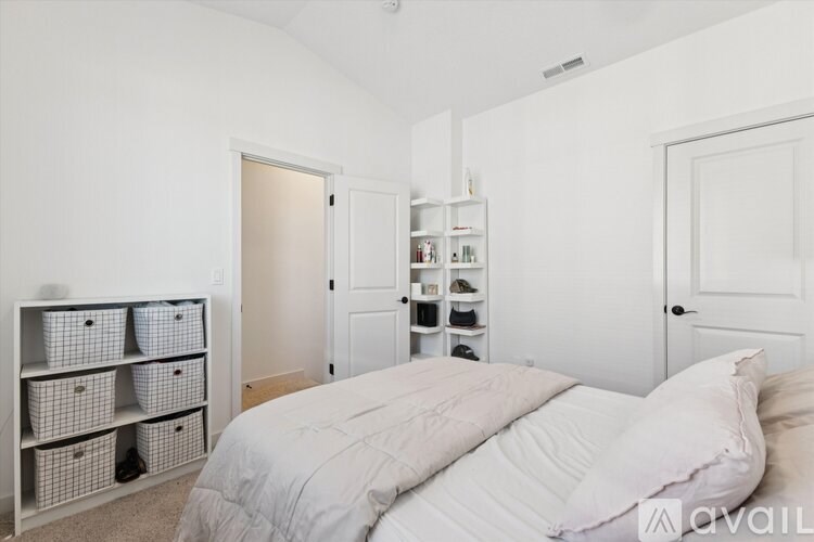 A bedroom with a bed, a shelf with baskets, and a closet.