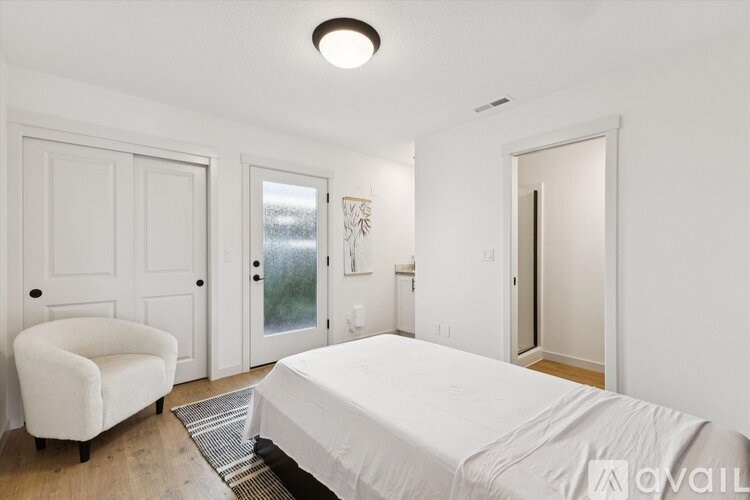 A bedroom with a bed, chair, and a window.