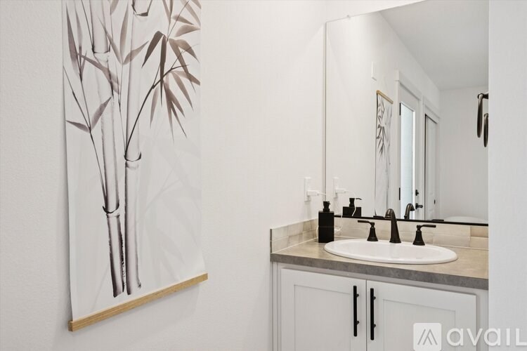 A bathroom with a white sink and a painting of a tree on the wall.