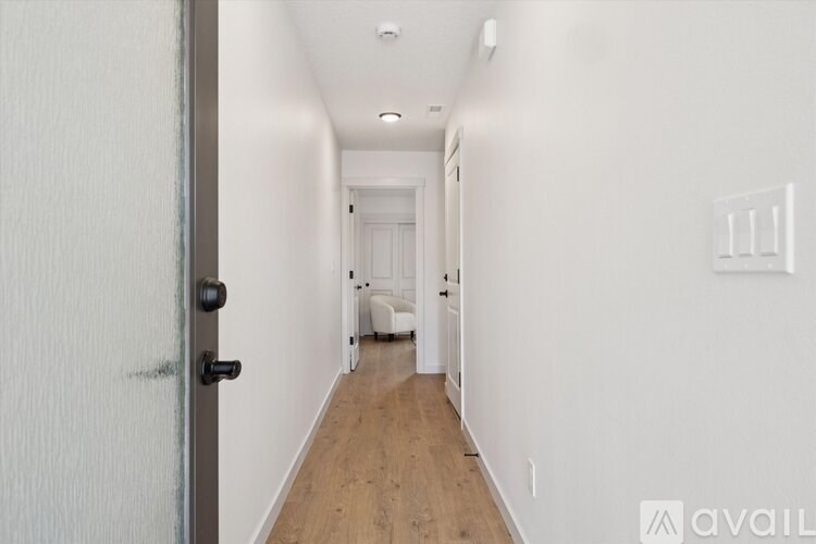 A long hallway with a door on the left and a light switch on the wall.