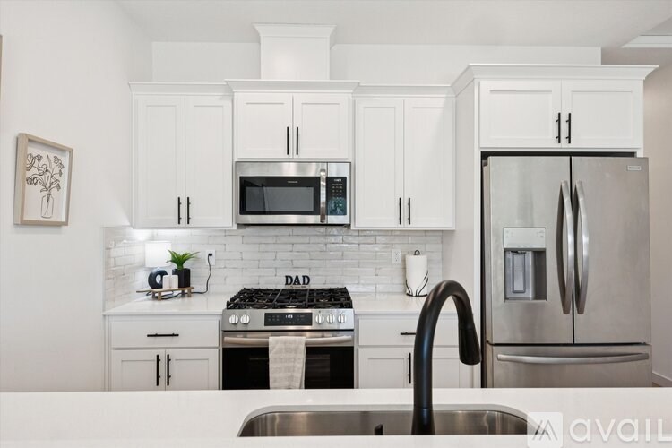 A modern kitchen with white cabinets and stainless steel appliances.