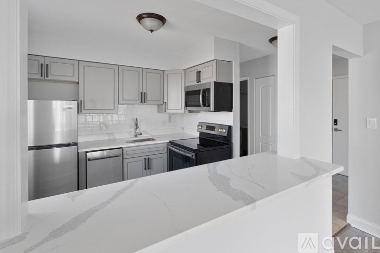 A kitchen with a white counter top and stainless steel appliances.