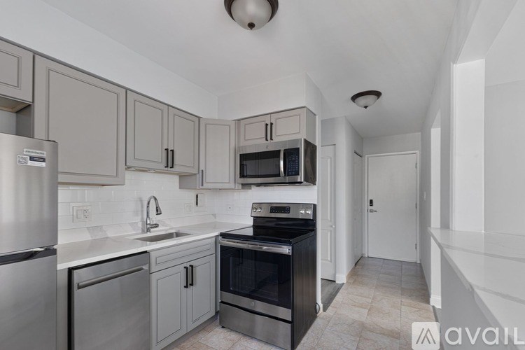 A kitchen with a stainless steel refrigerator, a black oven, and a white countertop.