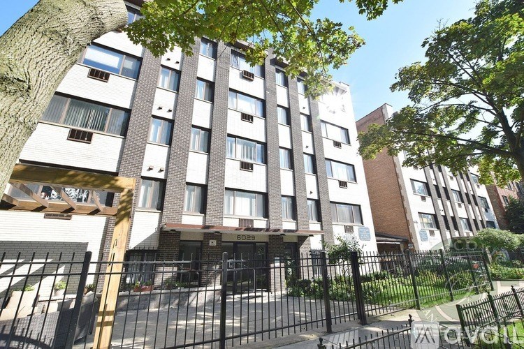A tall residential building with a black gate in front.