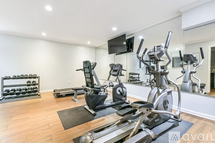 A well-lit home gym with a variety of exercise equipment.