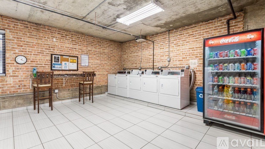 A Coca-Cola vending machine sits in a room with a brick wall and a white floor.