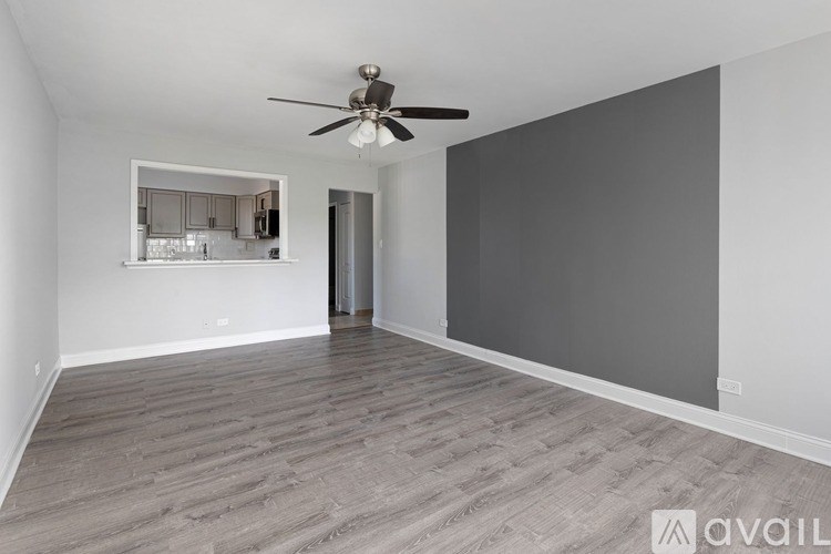 A spacious room with a ceiling fan and a view into a kitchen.