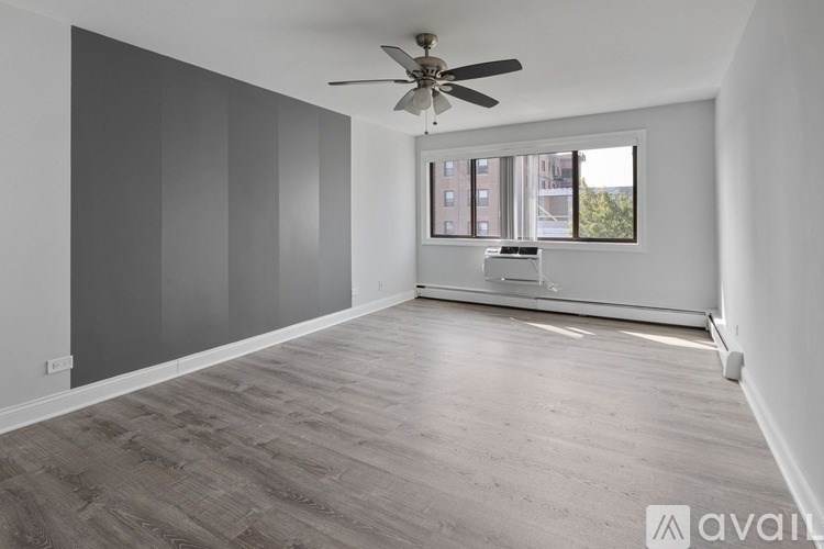 A spacious room with a ceiling fan and a window overlooking a cityscape.