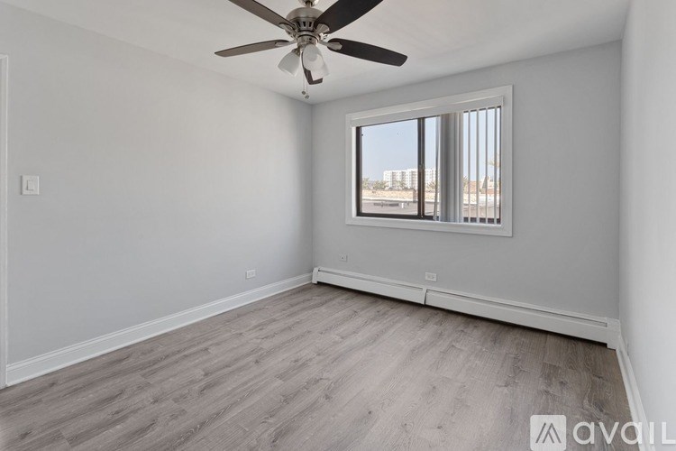 A room with a ceiling fan and a window overlooking a cityscape.