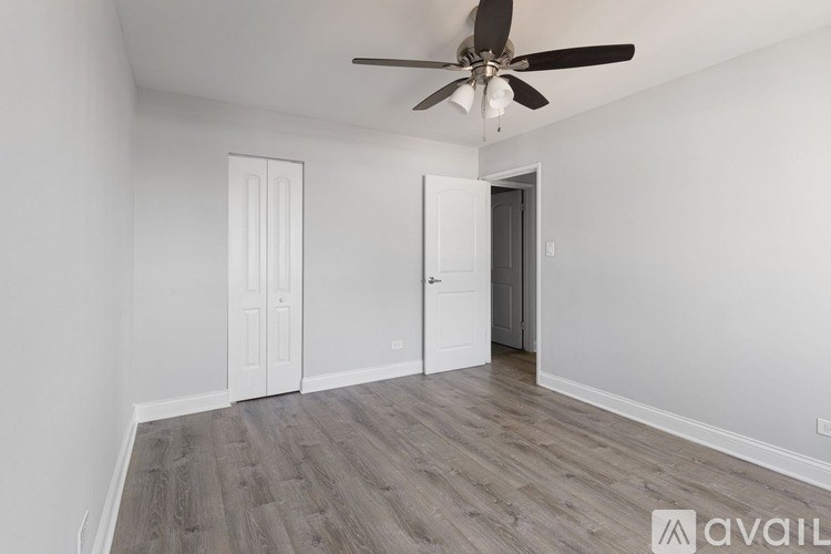 A room with a ceiling fan and wooden flooring.