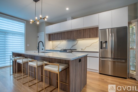 A modern kitchen with wooden stools and a stainless steel refrigerator.