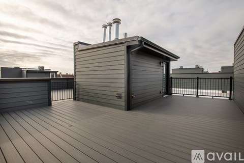A wooden deck with a small building and a metal railing.