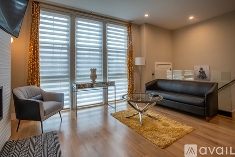 A living room with a black couch, a glass coffee table, and a television.