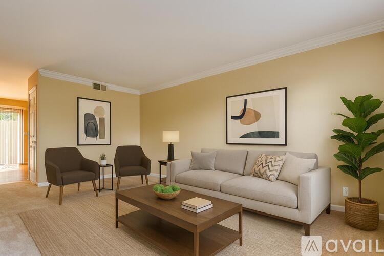 A living room with a white couch, two chairs, a coffee table, and a plant.