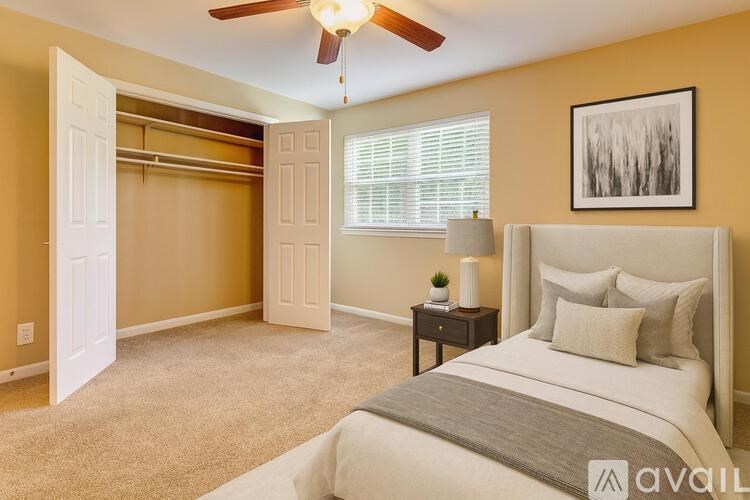 A bedroom with a large bed, a ceiling fan, and a painting on the wall.