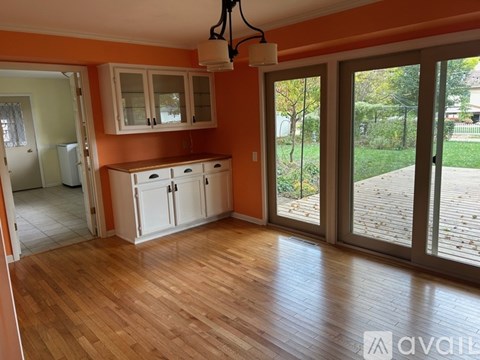A kitchen with orange walls and wooden floors is shown.