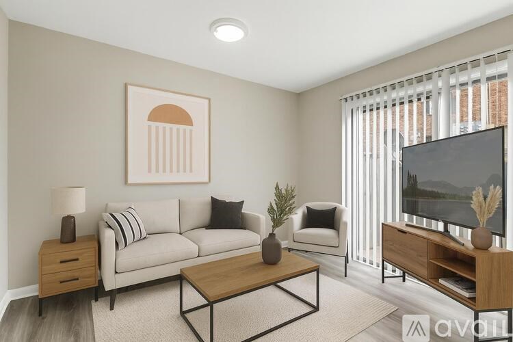 A living room with a grey couch, a coffee table, a lamp, a potted plant, and a television.