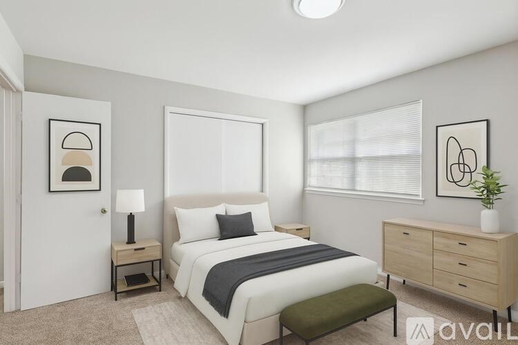 A bedroom with a bed, nightstand, and a plant.