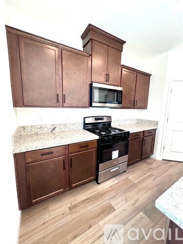 A kitchen with brown cabinets and a granite countertop.