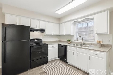 A kitchen with black appliances and white cabinets.