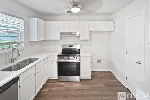 A kitchen with white cabinets and a wooden floor.