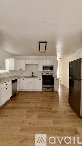A kitchen with white cabinets and a black fridge.