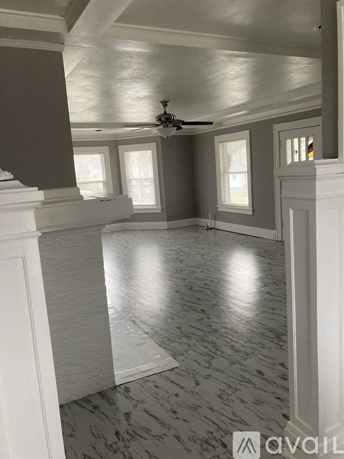 A room with a ceiling fan and marble flooring.