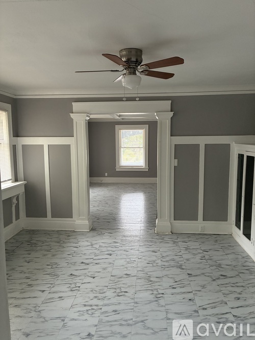 A room with a fan and marble flooring.
