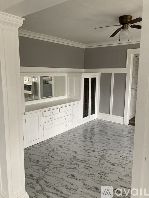 A room with a ceiling fan and a marble floor.