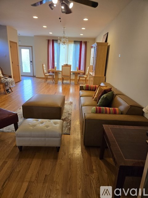 A living room with a brown couch and a white ottoman.