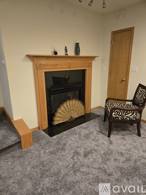 A room with a fireplace, a chair and a fan.