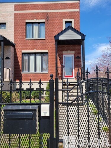 A red brick house with a black fence in front.
