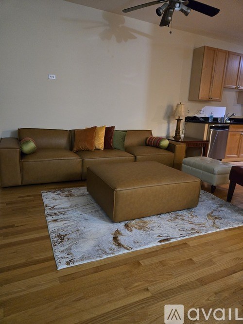 A living room with a brown couch and a rug.