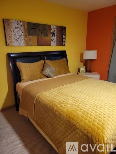 A bed with a yellow cover and a lamp on the side table.