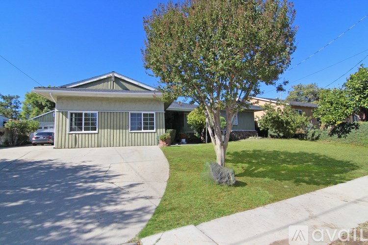 A house with a green lawn and a tree in front.