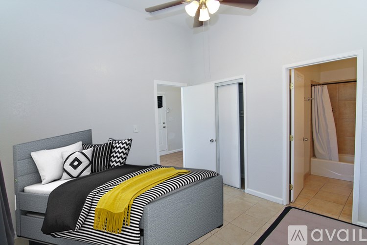 A bedroom with a bed, a ceiling fan, and a bathroom with a shower.