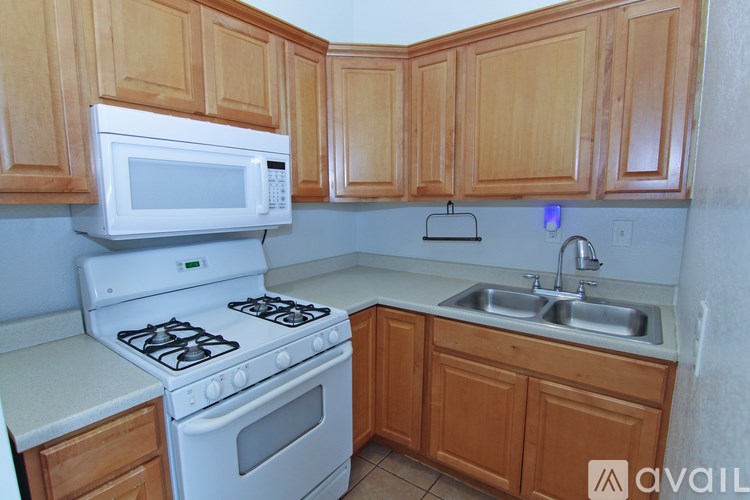 A kitchen with a white stove, white microwave, and wooden cabinets.