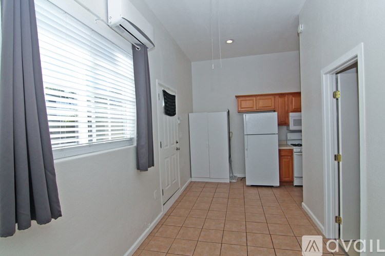 A kitchen with a refrigerator, a sink, and a window with curtains.