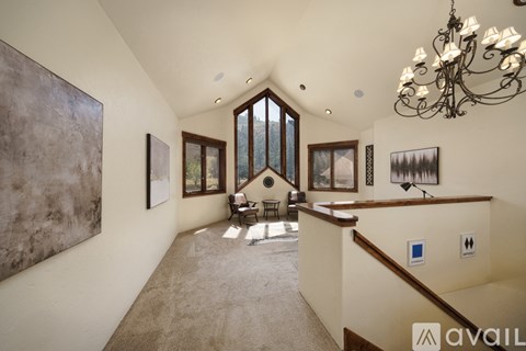A spacious living room with a large chandelier and a painting on the wall.