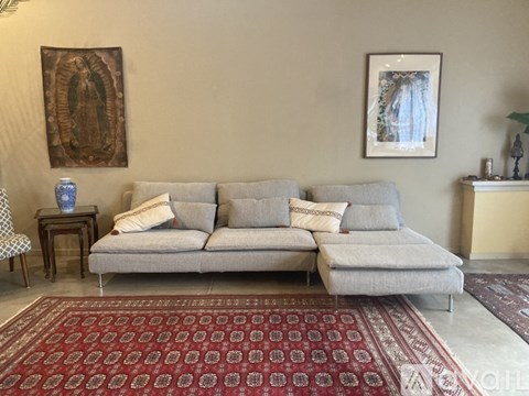 A living room with a grey couch and a red patterned rug.