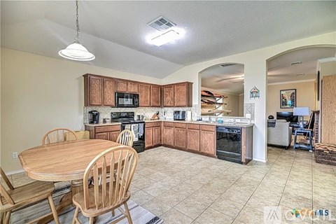 A kitchen with wooden cabinets and a table with chairs.