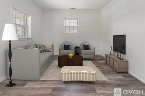 A living room with a grey couch, a brown ottoman, and a television on a wooden stand.
