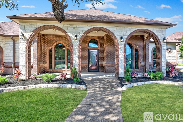 A house with a red brick archway entrance and a tree in front.