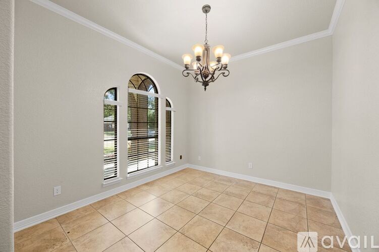 A room with a chandelier, tiled floor, and arched windows.
