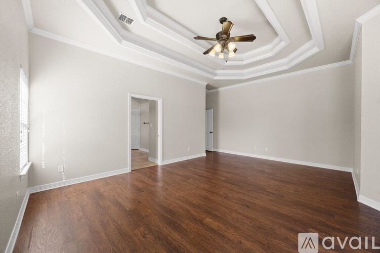 A room with a ceiling fan and wooden flooring.