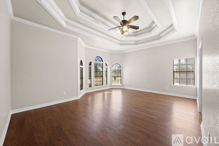 A spacious room with wood flooring and a ceiling fan.
