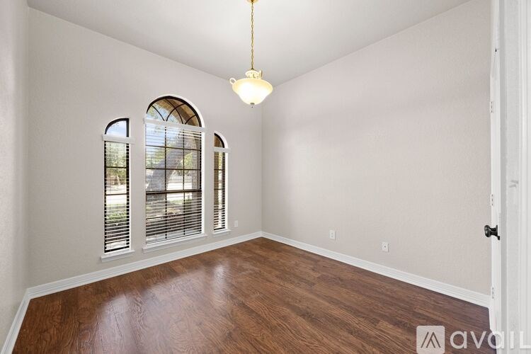 A room with wooden floors and a chandelier hanging from the ceiling.