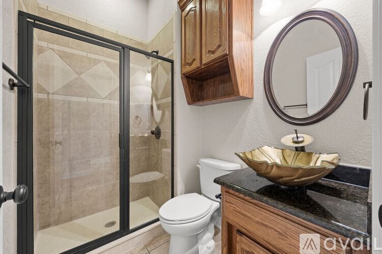 A bathroom with a toilet, a bowl sink, and a shower.